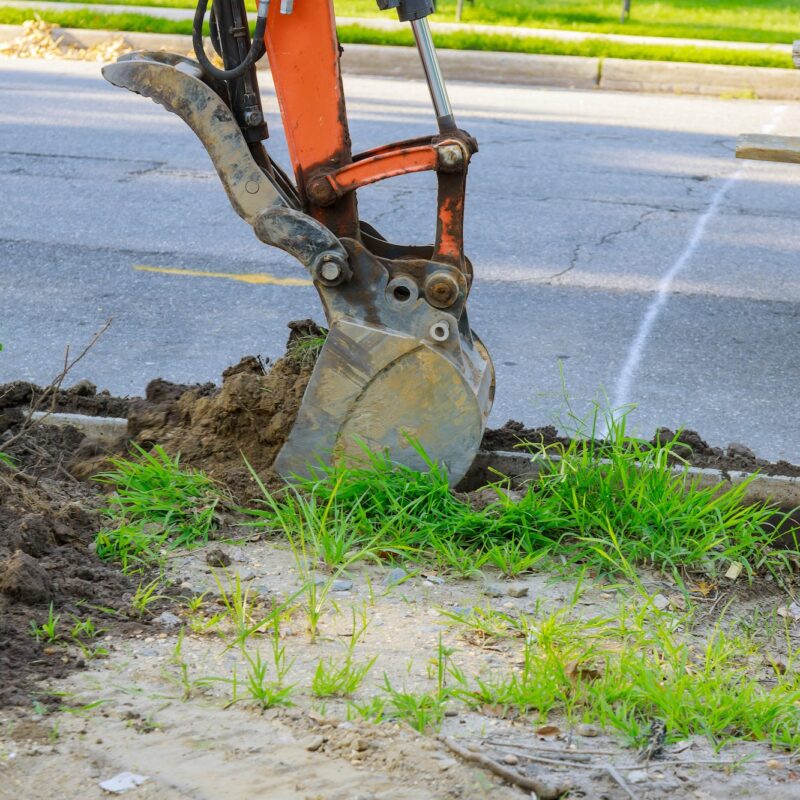 Urban municipal tractor with ladle is dig the sewer